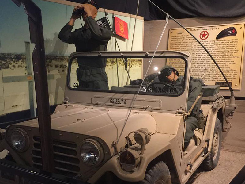 Museum exhibit of two Army Soldiers in four-wheeled vehicle.